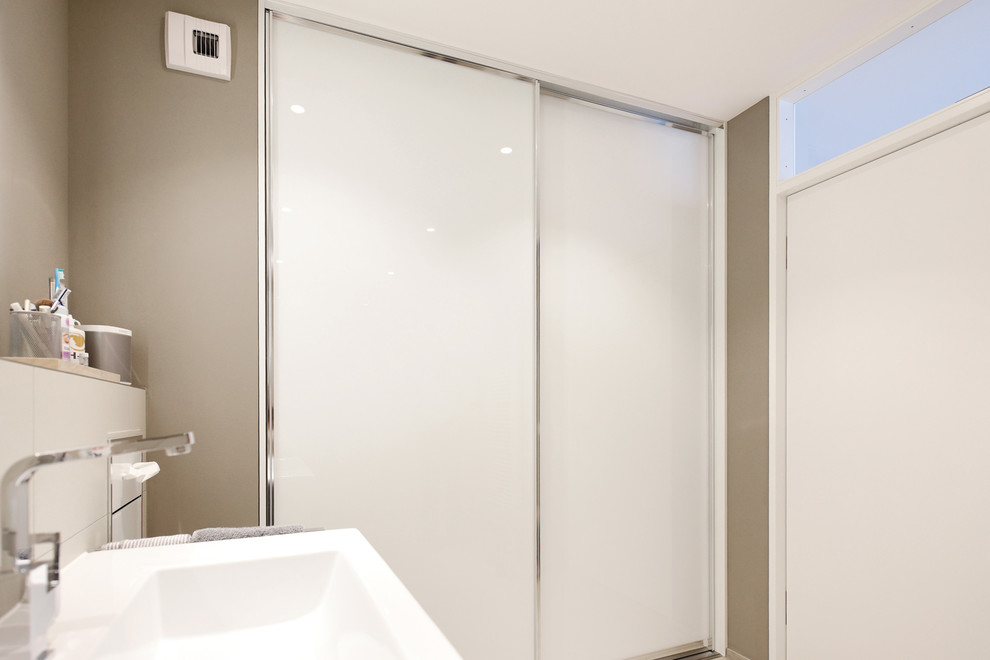 Kleines Modernes Duschbad mit Glasfronten, weißen Schränken und beigem Boden in Stuttgart