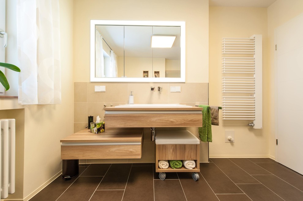 На фото: ванная комната среднего размера в средиземноморском стиле с фасадами цвета дерева среднего тона, серой плиткой, бежевыми стенами, накладной раковиной и столешницей из дерева