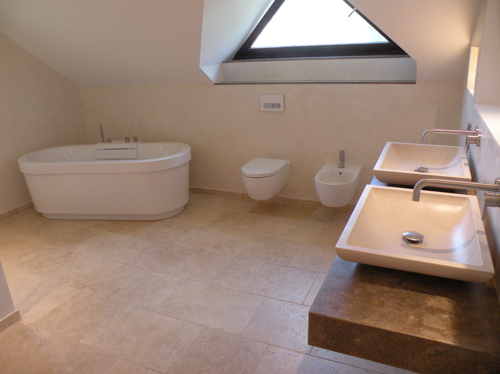 Idéer för stora maritima badrum, med ett fristående badkar, en kantlös dusch, en toalettstol med separat cisternkåpa, stenhäll, travertin golv, ett fristående handfat och bänkskiva i kalksten
