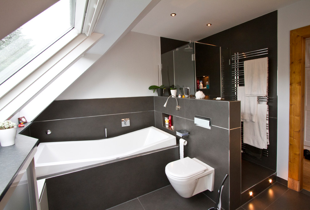 Kleines Modernes Badezimmer mit weißer Wandfarbe, Duschnische, schwarzen Fliesen, Badewanne in Nische und Wandtoilette in Hamburg