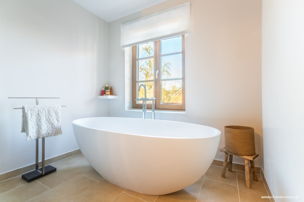 Mittelgroßes Modernes Badezimmer mit freistehender Badewanne, beigen Fliesen und weißer Wandfarbe in München