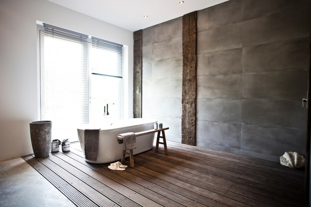Exempel på ett badrum, med ett fristående badkar, grå väggar och mörkt trägolv