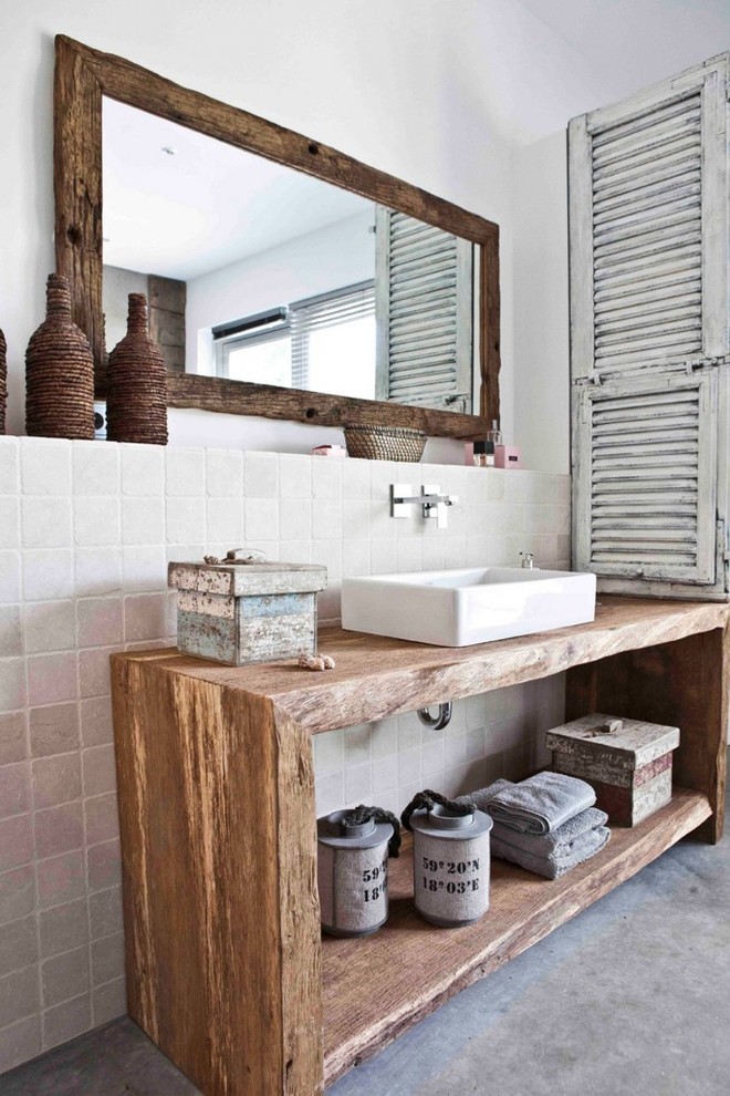 Cette image montre une salle de bain style shabby chic de taille moyenne avec un carrelage blanc, un carrelage de pierre, un mur blanc, une vasque, un plan de toilette en bois, sol en béton ciré et un placard sans porte.