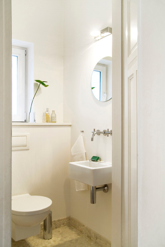 Small contemporary bathroom in Dusseldorf with a wall-mounted sink, a wall mounted toilet, white walls and pebble tile flooring.