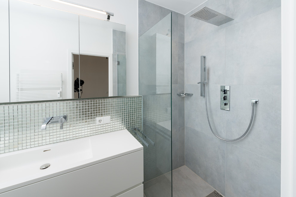 Mittelgroßes Modernes Badezimmer mit integriertem Waschbecken, flächenbündigen Schrankfronten, weißen Schränken, bodengleicher Dusche, grauen Fliesen, weißer Wandfarbe und Spiegelfliesen in München