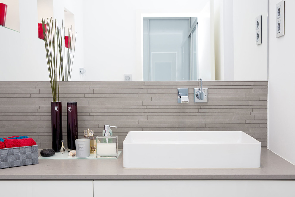 This is an example of a contemporary bathroom in Dortmund with grey tiles, matchstick tiles, a vessel sink and white walls.