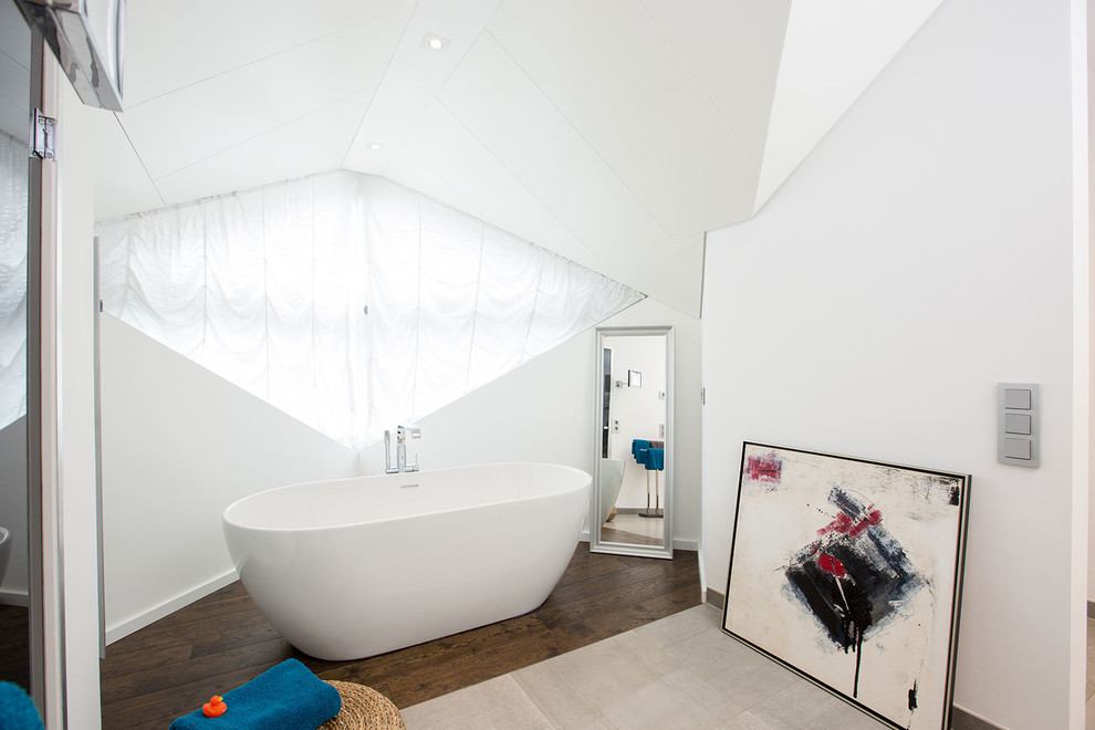 Réalisation d'une salle de bain principale design de taille moyenne avec une baignoire indépendante, un mur blanc et parquet foncé.