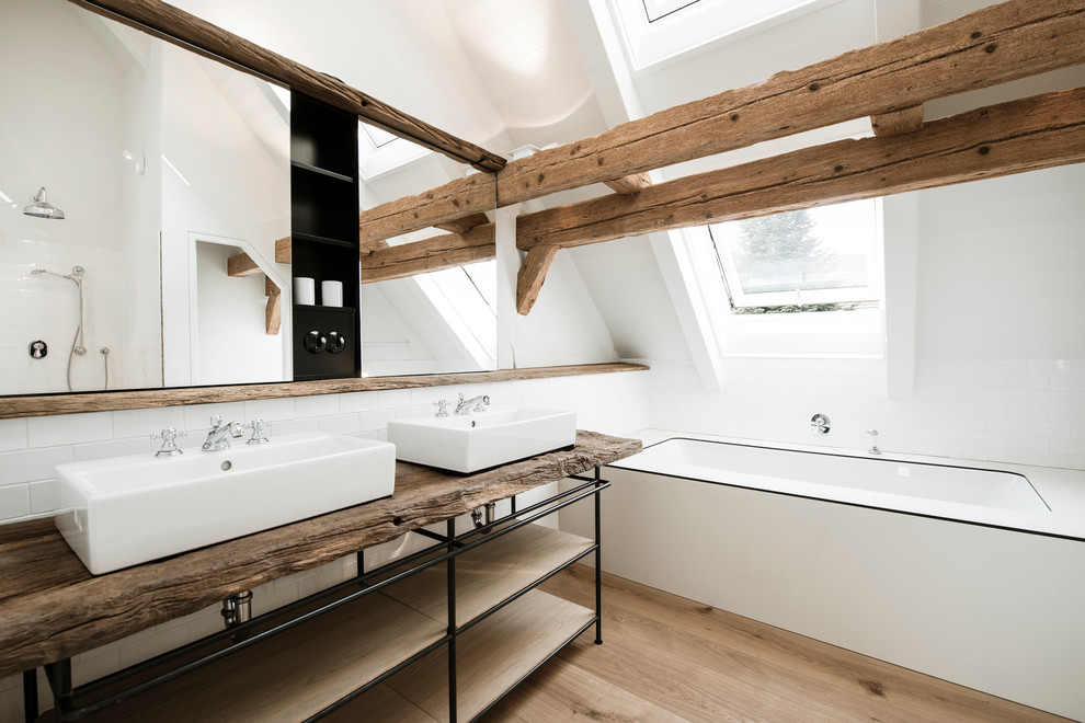 ミュンヘンにある中くらいな北欧スタイルのおしゃれな浴室 (白いタイル、サブウェイタイル、白い壁、無垢フローリング、木製洗面台、アンダーマウント型浴槽、ブラウンの洗面カウンター) の写真