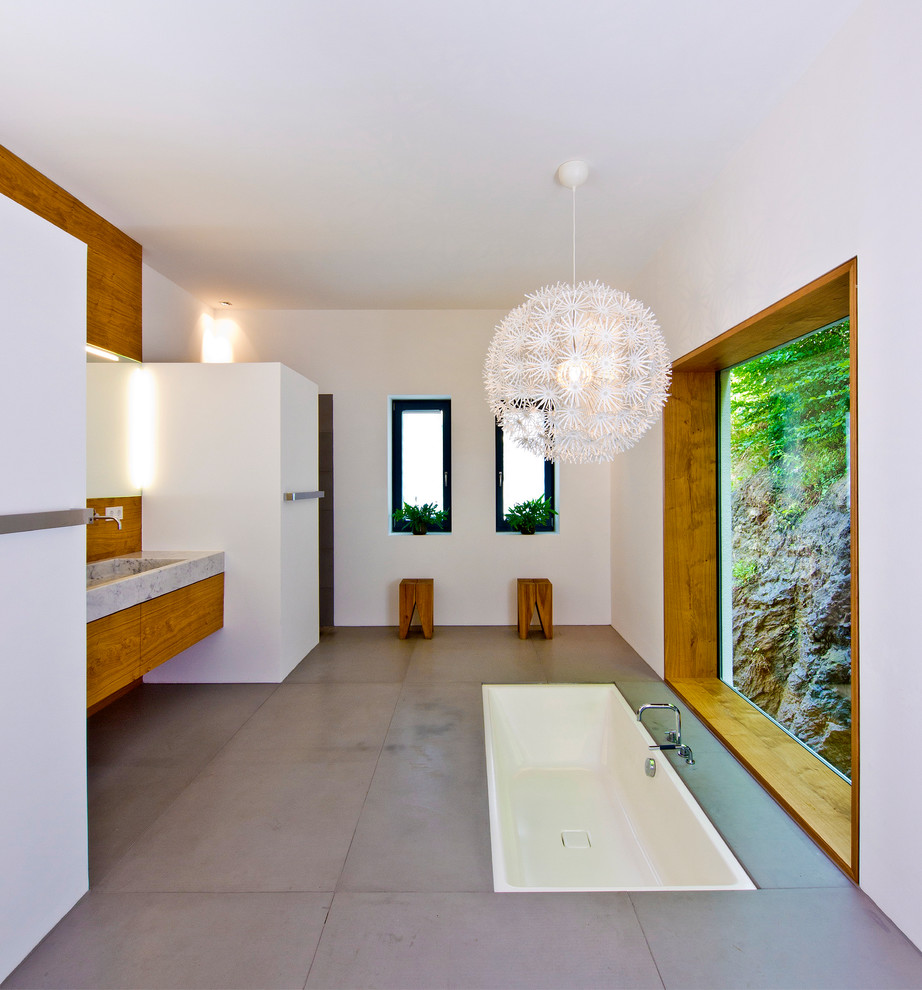 Mittelgroßes Modernes Badezimmer mit weißer Wandfarbe, grauem Boden, flächenbündigen Schrankfronten, braunen Schränken, Einbaubadewanne, Aufsatzwaschbecken und Waschtisch aus Holz in Sonstige