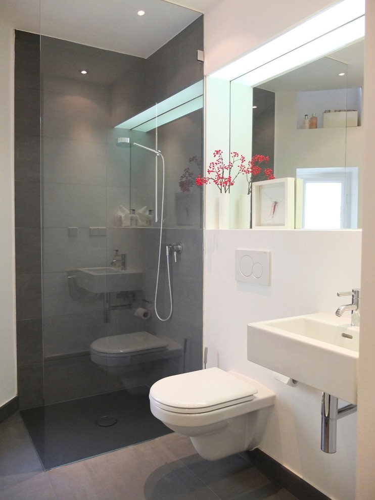 Idéer för ett litet modernt badrum med dusch, med ett väggmonterat handfat, en kantlös dusch, vita väggar, en vägghängd toalettstol och skiffergolv