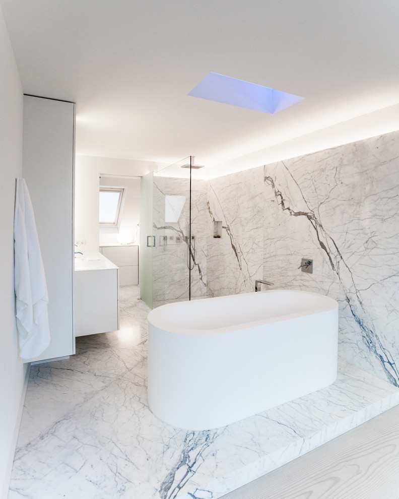 Idée de décoration pour une salle de bain design de taille moyenne avec un placard à porte plane, des portes de placard blanches, une douche ouverte, un carrelage gris, un carrelage blanc, un sol en marbre, un lavabo intégré, une baignoire indépendante et aucune cabine.