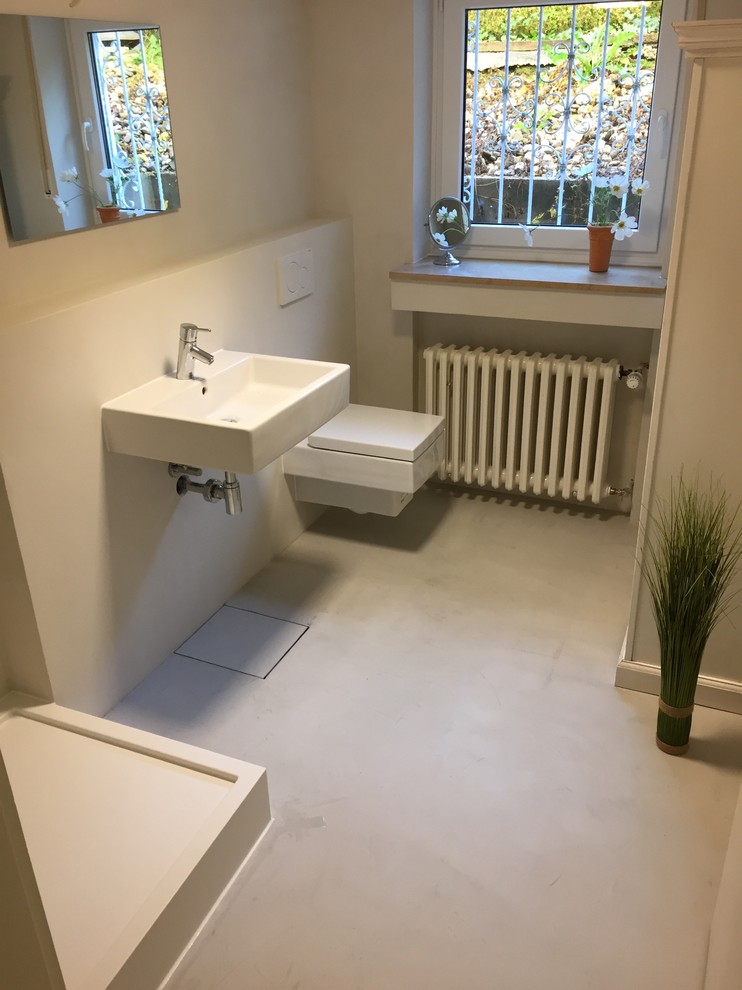 Example of a mid-sized trendy 3/4 white tile and stone tile concrete floor and gray floor bathroom design in Cologne with white walls, a wall-mount toilet and a wall-mount sink