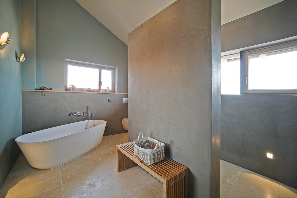 Источник вдохновения для домашнего уюта: главная ванная комната среднего размера в стиле модернизм с отдельно стоящей ванной, душем без бортиков, серыми стенами, полом из травертина, бежевым полом, открытым душем и раздельным унитазом