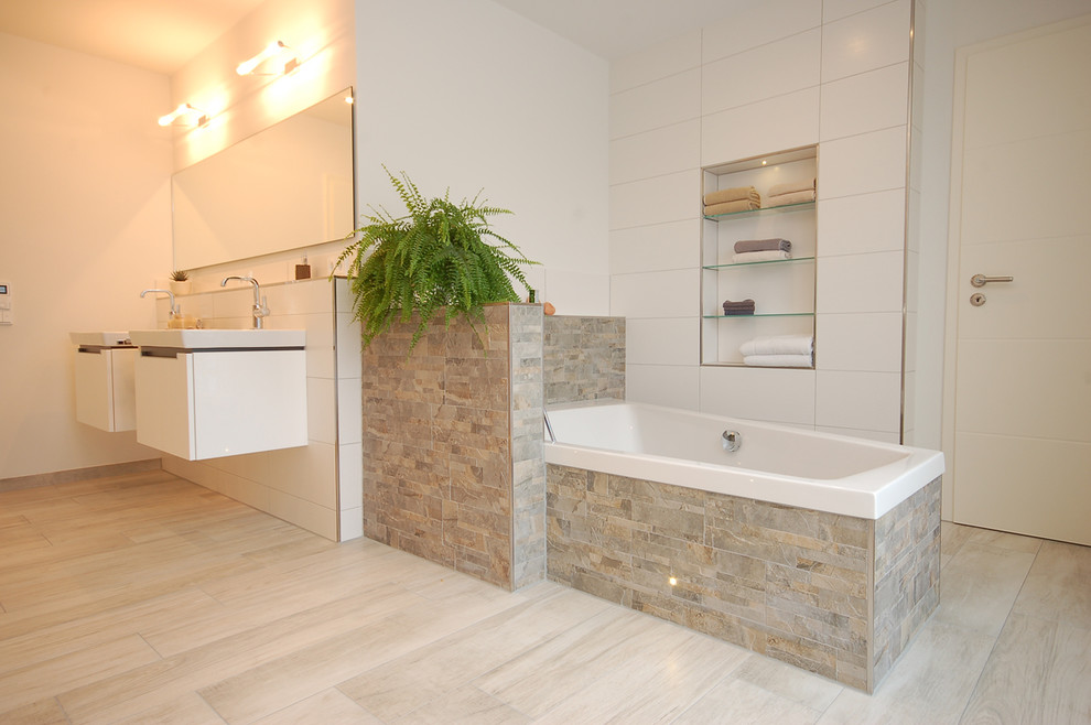 ブレーメンにある広いコンテンポラリースタイルのおしゃれな浴室 (アルコーブ型浴槽、白い壁、ベージュのタイル、グレーのタイル、白いタイル、ボーダータイル) の写真