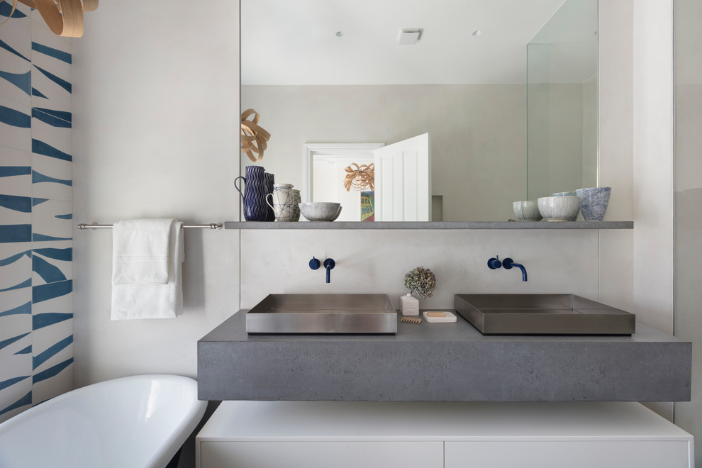 Inspiration for a large contemporary ensuite bathroom in London with flat-panel cabinets, white cabinets, a freestanding bath, blue tiles, white tiles, ceramic tiles, white walls, a vessel sink, grey worktops, a corner shower, concrete worktops and a hinged door.