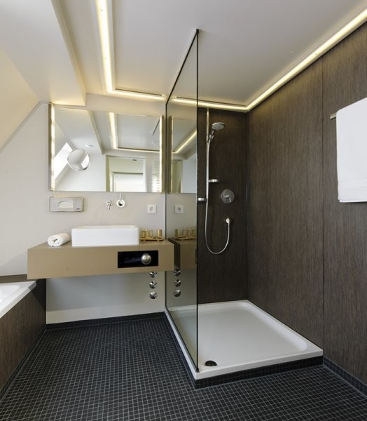 Inredning av ett modernt badrum, med ett platsbyggt badkar, en öppen dusch, brun kakel, beige väggar, mosaikgolv, ett fristående handfat, bänkskiva i betong, brunt golv och med dusch som är öppen