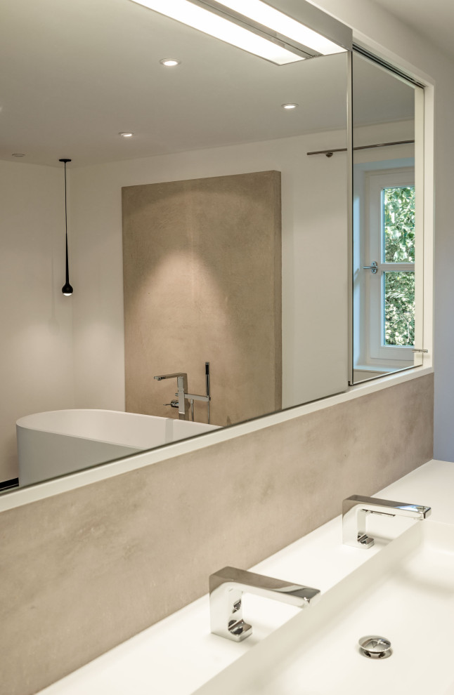 Modernes Badezimmer mit freistehender Badewanne, Mineralwerkstoff-Waschtisch und weißer Waschtischplatte in Sonstige