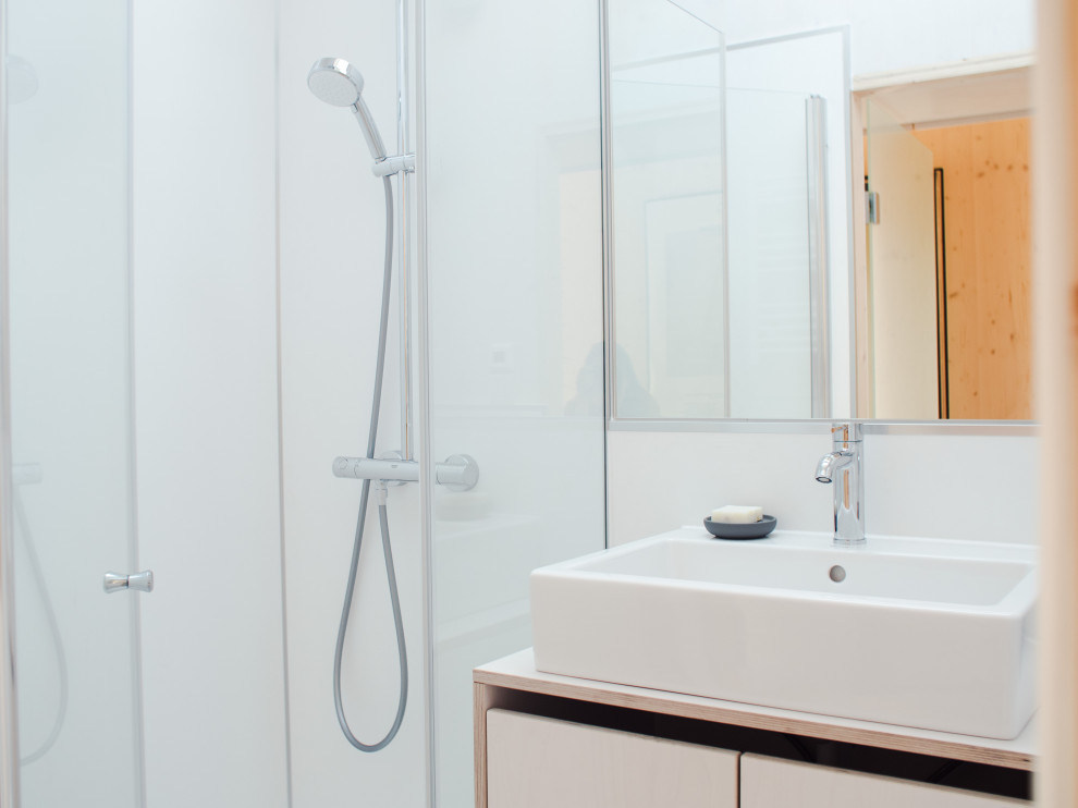 Idéer för att renovera ett litet funkis vit vitt badrum med dusch, med släta luckor, skåp i ljust trä, en dusch i en alkov, en toalettstol med separat cisternkåpa, vita väggar, linoleumgolv, ett fristående handfat, grått golv och dusch med gångjärnsdörr