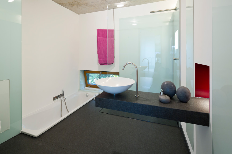 Inredning av ett modernt mellanstort svart svart badrum med dusch, med ett platsbyggt badkar, en kantlös dusch, vita väggar, ett fristående handfat, granitbänkskiva, svart golv och med dusch som är öppen