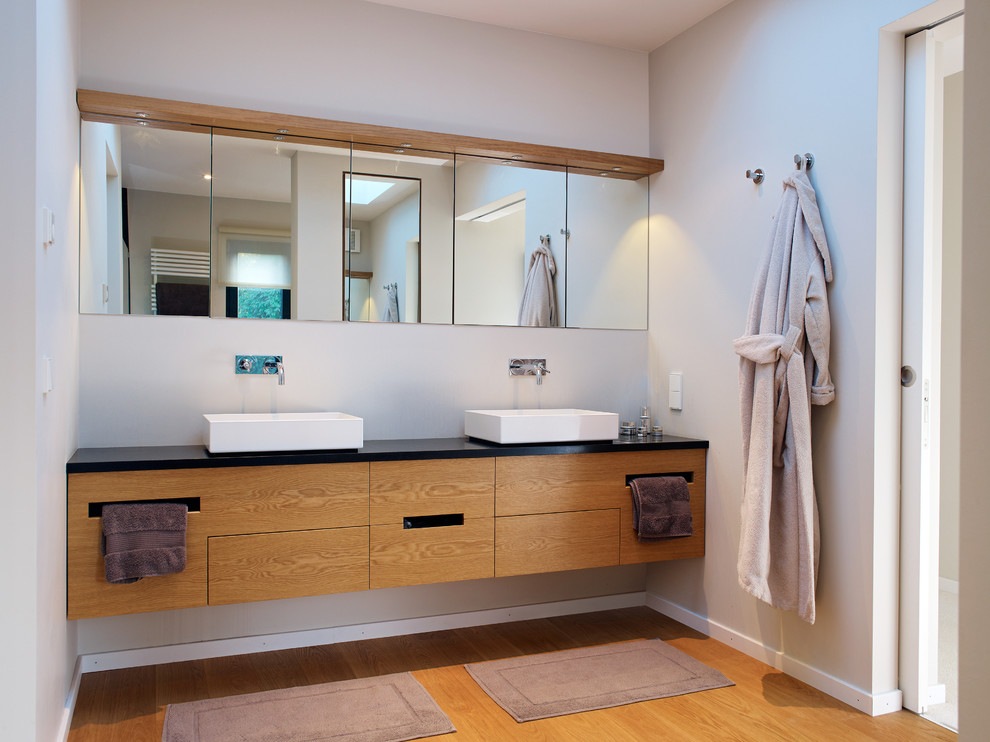Exemple d'une salle de bain tendance en bois brun de taille moyenne avec un placard à porte plane, un mur beige, un sol en bois brun et une vasque.