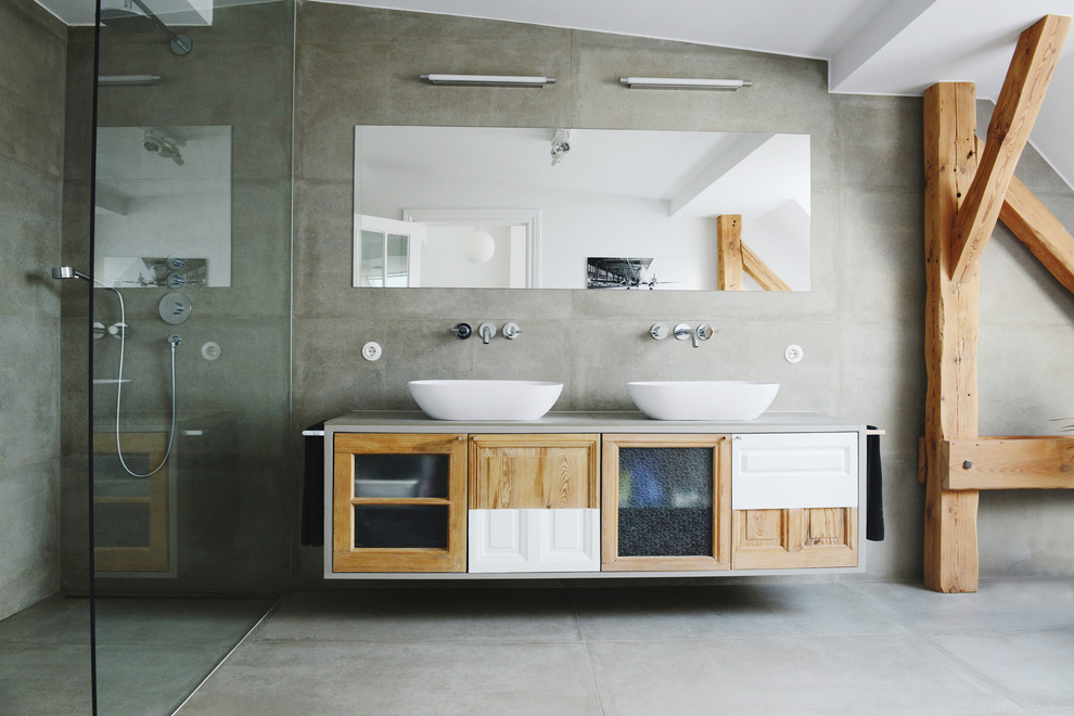 This is an example of an expansive contemporary bathroom in Berlin with a built-in shower, grey tiles, grey walls, concrete flooring, a vessel sink, concrete worktops and medium wood cabinets.