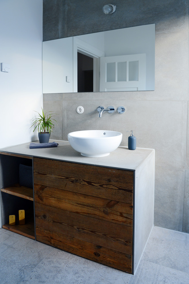 Ejemplo de cuarto de baño actual con armarios abiertos, puertas de armario de madera en tonos medios, paredes grises, suelo de cemento, lavabo sobreencimera y encimera de cemento