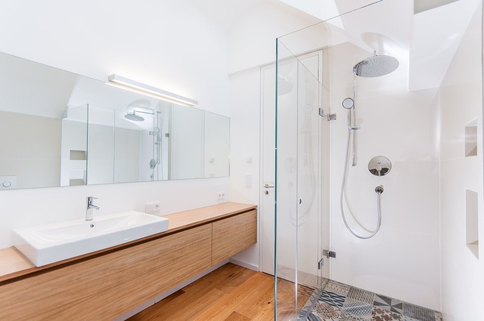 Cette photo montre une salle de bain tendance en bois brun de taille moyenne avec un placard à porte plane, une douche d'angle, un carrelage multicolore, un mur blanc, un plan de toilette en bois, des carreaux de céramique, un sol en bois brun et une vasque.