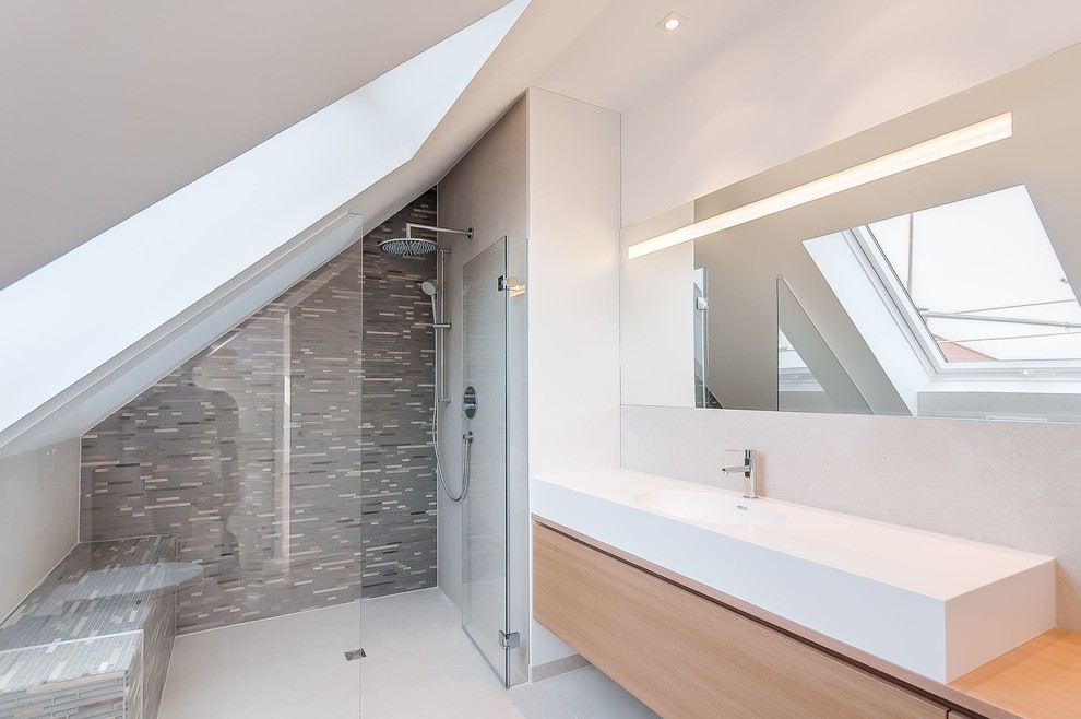 Foto på ett mellanstort funkis brun badrum med dusch, med grå kakel, mosaik, ett integrerad handfat, släta luckor, skåp i mellenmörkt trä, träbänkskiva och vita väggar