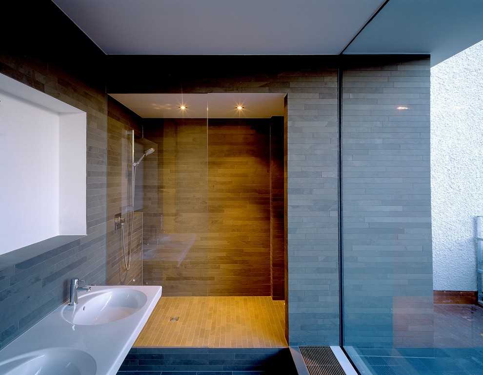 На фото: большая ванная комната в стиле модернизм с монолитной раковиной, душем в нише, серой плиткой, удлиненной плиткой, серыми стенами и полом из сланца