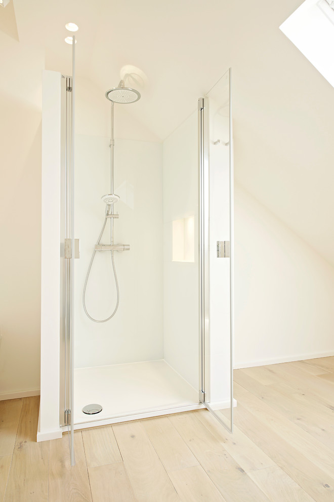 Exempel på ett modernt badrum med dusch, med vita skåp, träbänkskiva, en kantlös dusch, vita väggar och ljust trägolv