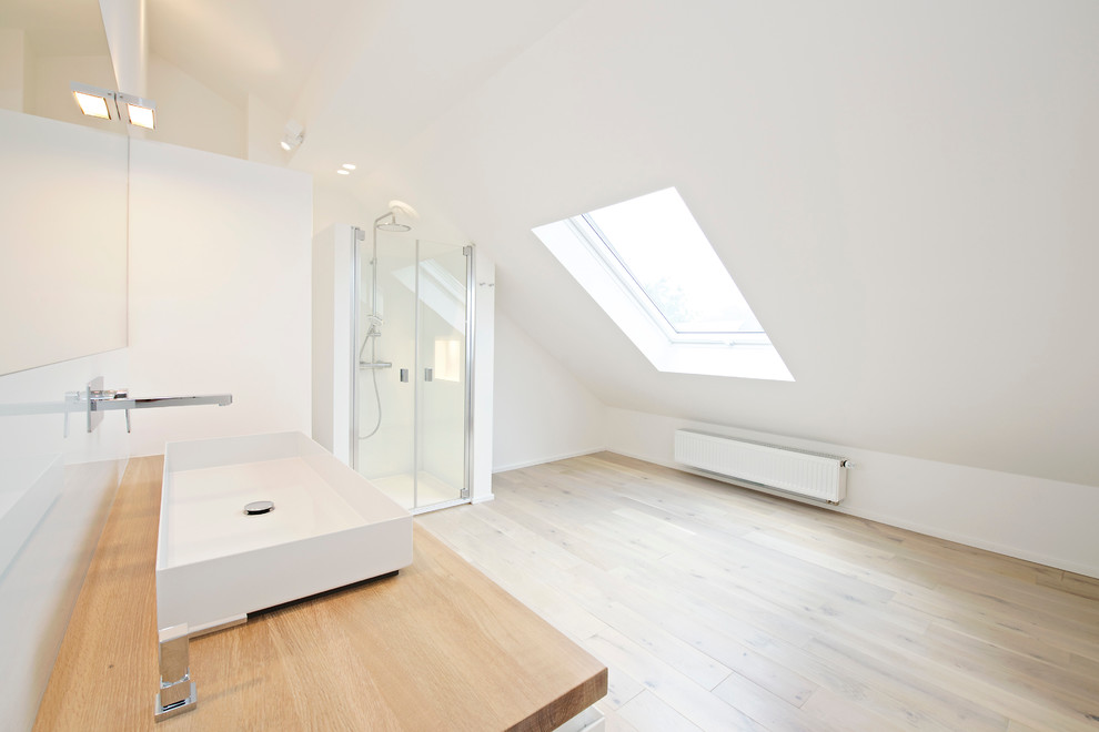 Ejemplo de cuarto de baño actual con lavabo de seno grande, puertas de armario blancas, encimera de madera, ducha a ras de suelo y paredes blancas