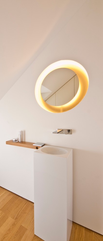 На фото: ванная комната в стиле модернизм с раковиной с пьедесталом, белыми стенами и паркетным полом среднего тона с