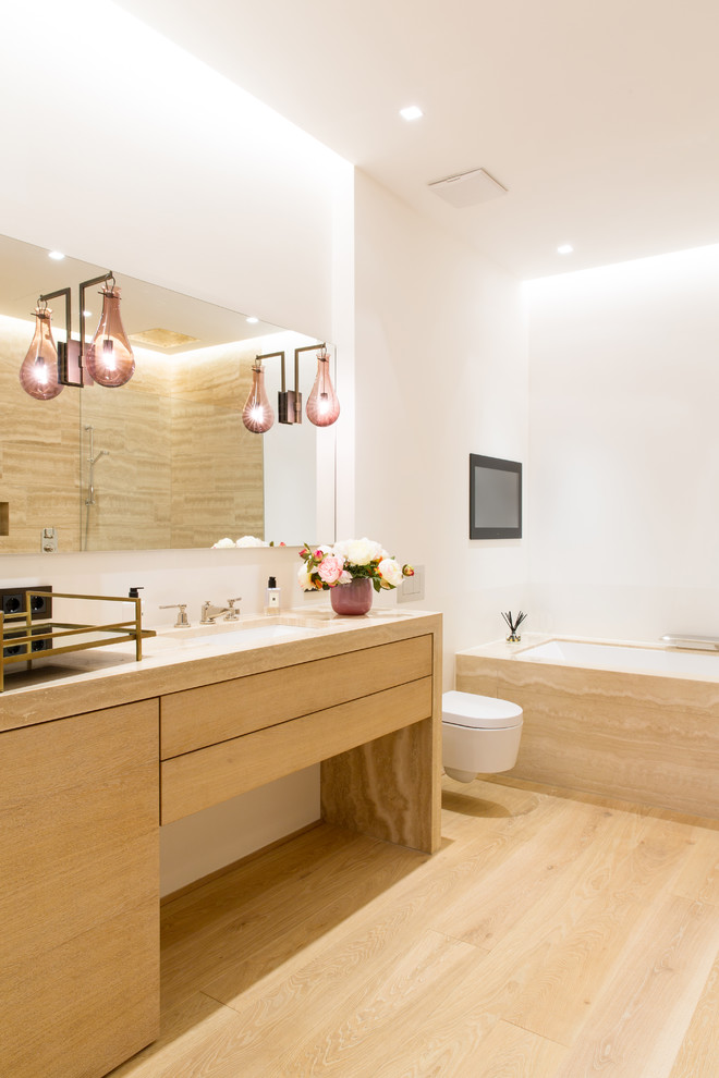Inspiration for a mid-sized contemporary master light wood floor and beige floor drop-in bathtub remodel in Munich with flat-panel cabinets, light wood cabinets, a wall-mount toilet, white walls, beige countertops, an undermount sink and wood countertops