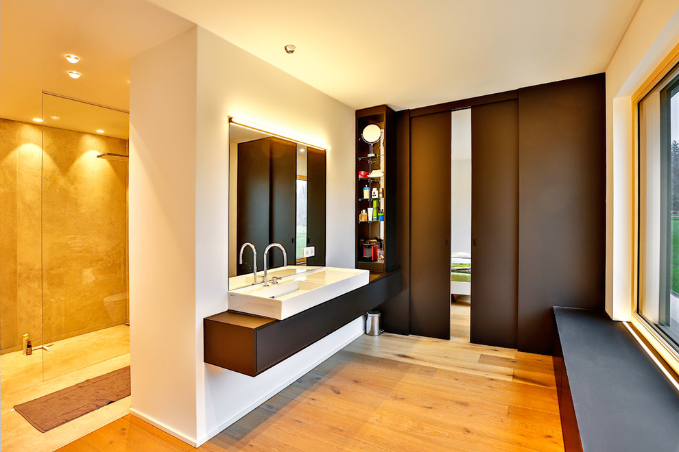 Mittelgroßes Modernes Badezimmer En Suite mit flächenbündigen Schrankfronten, schwarzen Schränken, weißer Wandfarbe, braunem Holzboden, Aufsatzwaschbecken, braunem Boden und schwarzer Waschtischplatte in Stuttgart