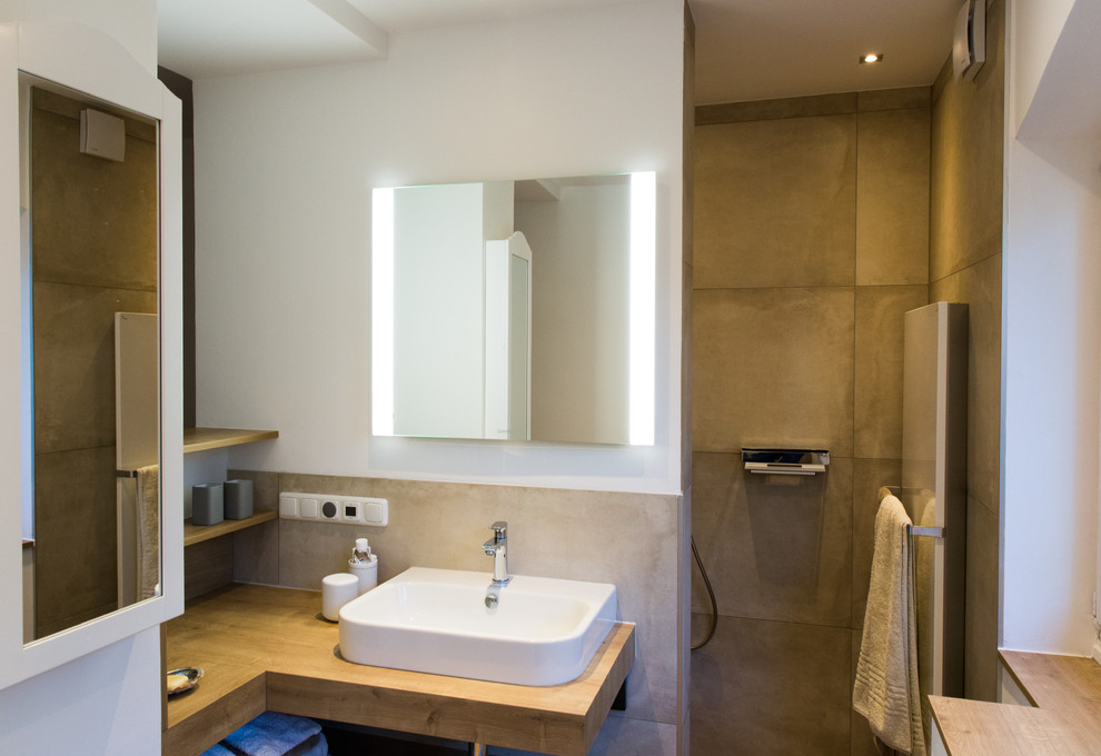 Exempel på ett mellanstort medelhavsstil badrum med dusch, med öppna hyllor, skåp i ljust trä, en kantlös dusch, en vägghängd toalettstol, beige kakel, stenkakel, beige väggar, cementgolv, ett fristående handfat, träbänkskiva, beiget golv och med dusch som är öppen