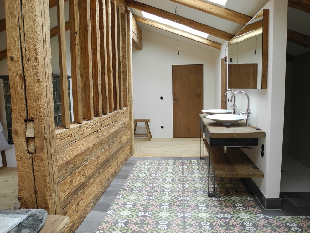 Cette image montre une grande salle de bain rustique avec une vasque, un placard sans porte, un mur blanc, un plan de toilette en bois et un plan de toilette marron.