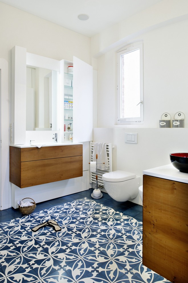 Photo of a large contemporary ensuite bathroom in Stuttgart with flat-panel cabinets, brown cabinets, an alcove bath, a built-in shower, a wall mounted toilet, mosaic tile flooring, an integrated sink, solid surface worktops, blue floors and white worktops.