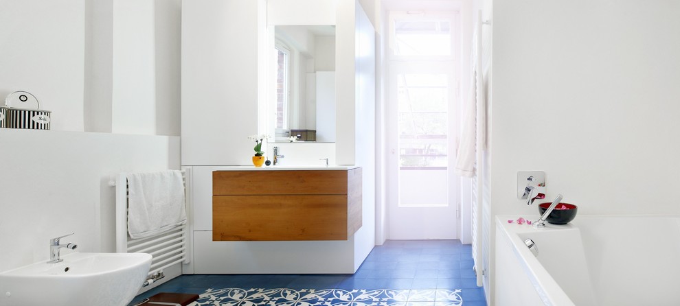 Cette image montre une grande salle de bain principale design avec un placard à porte plane, des portes de placard oranges, une baignoire en alcôve, un espace douche bain, un bidet, un sol en carrelage de terre cuite, un lavabo intégré, un plan de toilette en surface solide, un sol bleu et un plan de toilette blanc.