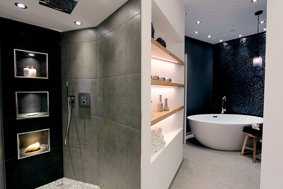 Ispirazione per una stanza da bagno design con vasca freestanding, doccia a filo pavimento, piastrelle grigie, piastrelle a mosaico, pareti grigie e pavimento con piastrelle di ciottoli