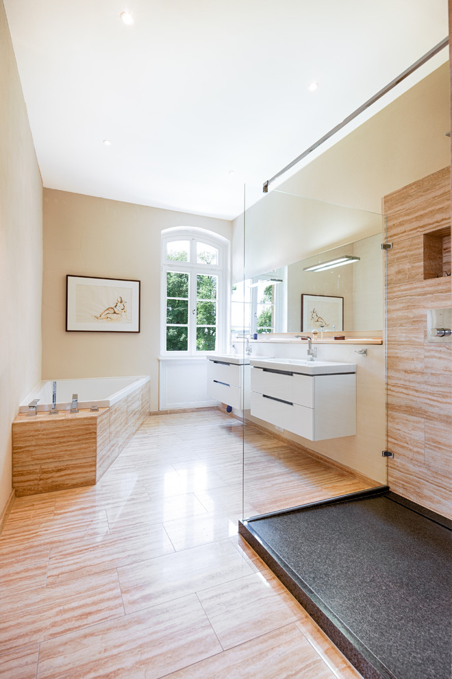 Exempel på ett stort klassiskt badrum med dusch, med ett hörnbadkar, en kantlös dusch, brun kakel, travertinkakel, beige väggar, travertin golv, ett integrerad handfat, bänkskiva i akrylsten, beiget golv, med dusch som är öppen, släta luckor och vita skåp