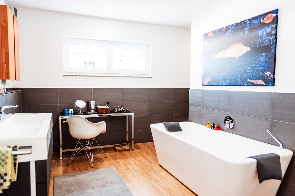 На фото: огромная главная ванная комната в современном стиле с открытыми фасадами, отдельно стоящей ванной, душем без бортиков, серой плиткой, керамической плиткой, белыми стенами, полом из бамбука и настольной раковиной