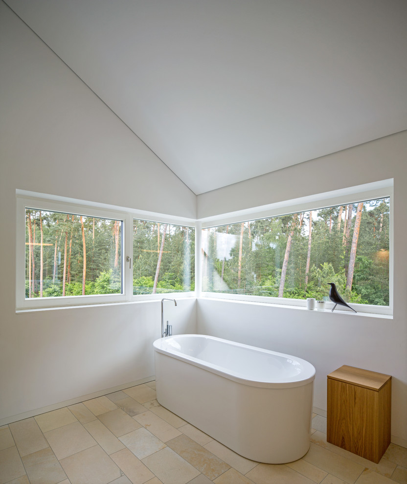Inspiration pour une salle de bain design de taille moyenne avec une baignoire indépendante, un mur blanc et un sol en calcaire.
