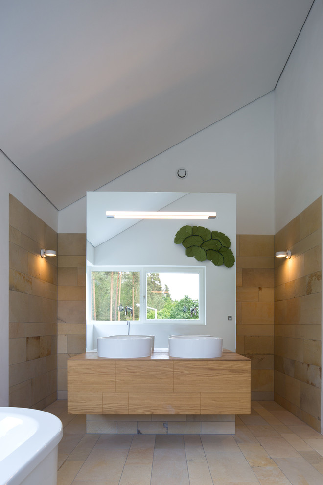 Aménagement d'une salle de bain contemporaine en bois brun de taille moyenne avec des dalles de pierre, un mur blanc, un sol en calcaire, une vasque, un plan de toilette en bois, un plan de toilette marron, un placard à porte plane, une baignoire indépendante, meuble double vasque et meuble-lavabo suspendu.