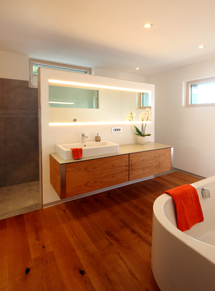 Foto på ett mellanstort funkis beige en-suite badrum, med släta luckor, skåp i mellenmörkt trä, ett fristående badkar, brun kakel, vita väggar, mellanmörkt trägolv, ett fristående handfat och brunt golv