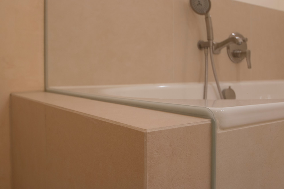 Modelo de cuarto de baño clásico con ducha abierta, sanitario de pared, baldosas y/o azulejos beige, bañera encastrada, paredes beige, suelo beige y ducha abierta