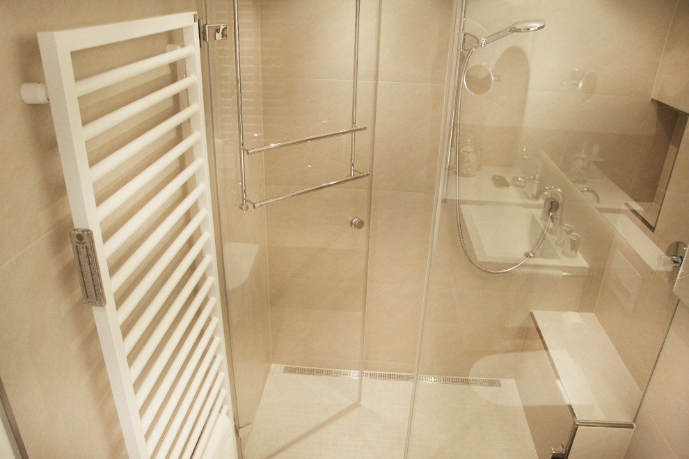Exemple d'une salle de bain tendance de taille moyenne avec un placard à porte plane, des portes de placard blanches, WC suspendus, un carrelage beige, un mur blanc, un lavabo suspendu, un sol beige et une cabine de douche à porte battante.