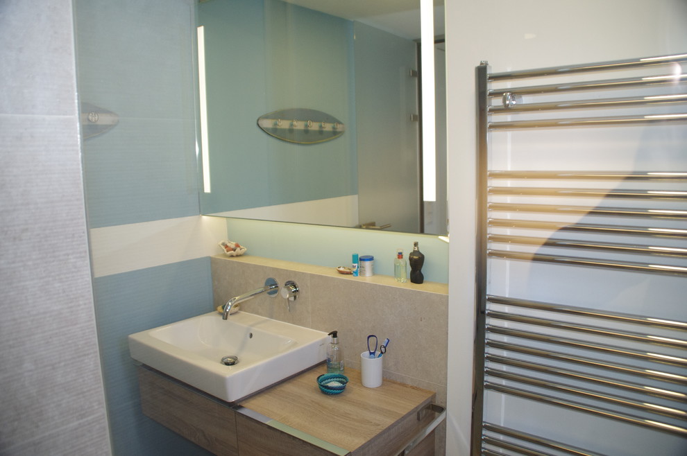 Imagen de cuarto de baño contemporáneo con armarios con paneles lisos, paredes azules, lavabo sobreencimera y sanitario de pared