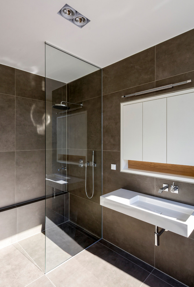 Idéer för ett mellanstort modernt badrum med dusch, med en kantlös dusch, brun kakel, ett väggmonterat handfat, bruna väggar, släta luckor, vita skåp, ett platsbyggt badkar och keramikplattor