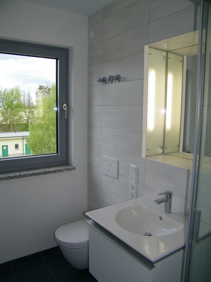 Kleines Modernes Duschbad mit bodengleicher Dusche, Wandtoilette mit Spülkasten, weißer Wandfarbe, Keramikboden, integriertem Waschbecken und Falttür-Duschabtrennung in Dresden
