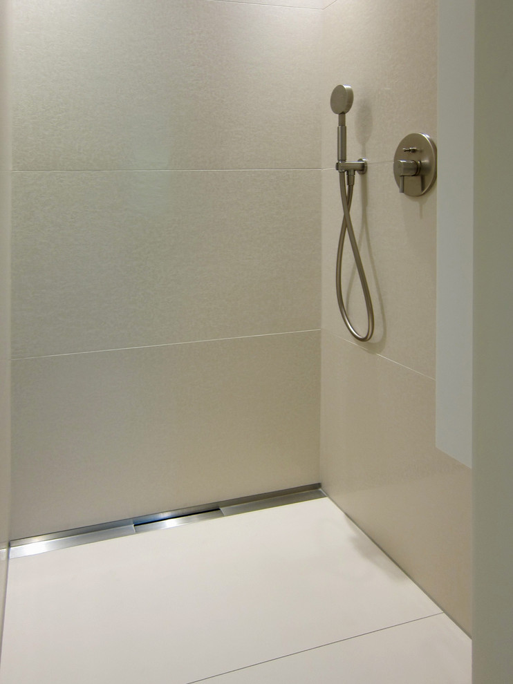 Exemple d'une salle de bain principale tendance de taille moyenne avec un placard à porte plane, des portes de placard blanches, une baignoire posée, une douche à l'italienne, WC suspendus, un carrelage noir, des carreaux de céramique, un mur blanc, un sol en carrelage de céramique, un lavabo posé et un plan de toilette en surface solide.